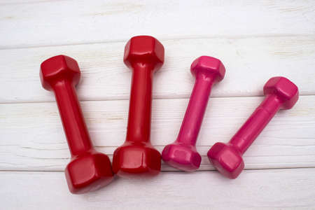 Red and pink dumbbells on a white wooden floorの写真素材