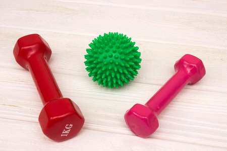 Red and pink dumbbells on a white wooden floorの写真素材