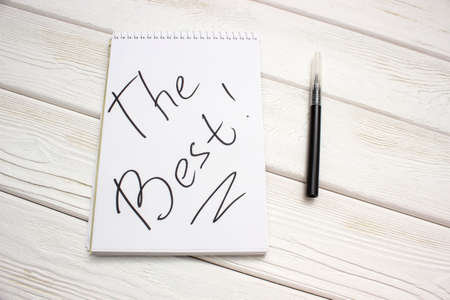 A notebook with an inscription is the best and black marker on white wooden tableの写真素材