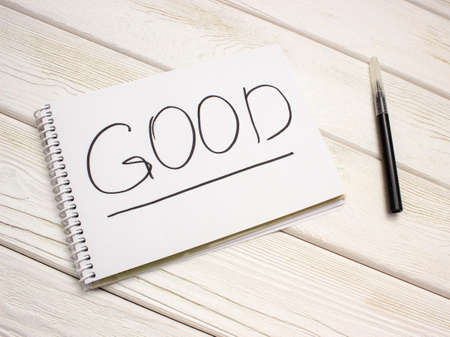A notebook with an inscription is good and black marker on white wooden tableの写真素材