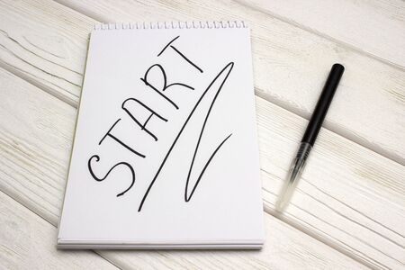 A notebook with an inscription is start and black marker on white wooden tableの写真素材
