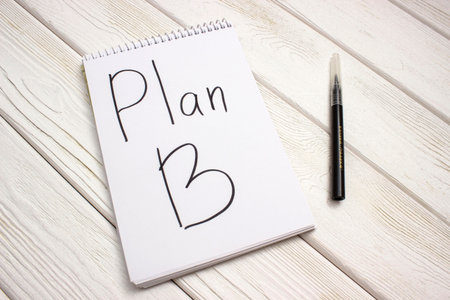 A notebook with an inscription is plan b and black marker on white wooden tableの写真素材