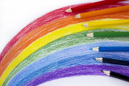 Colored pencils drawing a rainbow on a white sheet of paperの写真素材