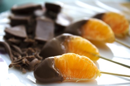Sweet mandarin in chocolate which lies on a plateの写真素材