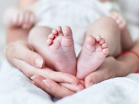 Baby's little feet, in a cradle of beautiful female hands, wrapped in maternal care and love
