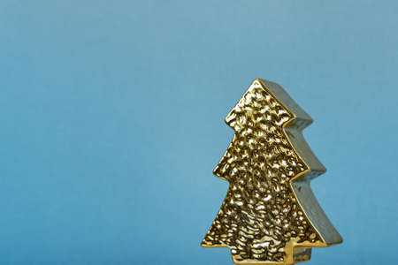 Christmas toy in the form of a golden tree on a uniform blue backgroundの写真素材