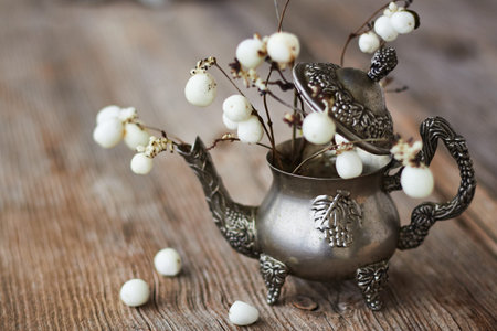 Still life of berries and a miniature silver teapot on a textured wooden surfaceの写真素材