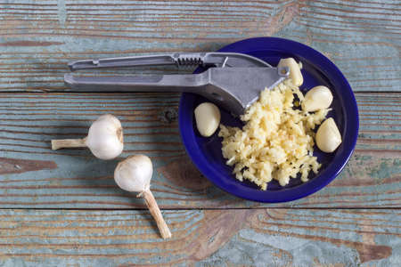 crushed fresh garlic press on a wooden boardの写真素材