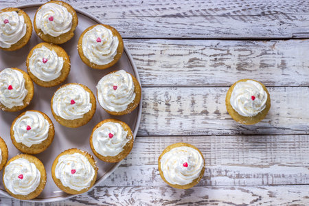 Cupcakes with white cream on a plate with decoration heart wooden white backgroundの写真素材