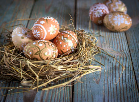 painted Easter eggs in a nest on a rustic wooden backgroundの写真素材