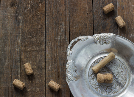 corkscrew and cork from wine on the old dark wooden background in metal plateの写真素材