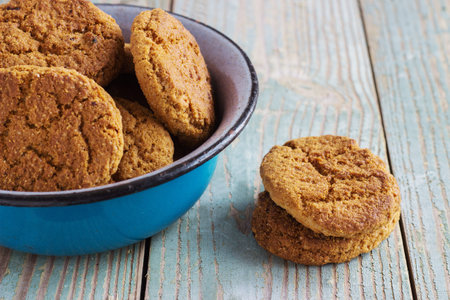Oatmeal cookies in a metal bowl with coffee beans on old wooden background