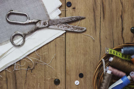 Vintage Background with sewing tools and colored tape Sewing kit. Scissors, bobbins with thread and needles on the old wooden backgroundの写真素材