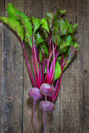 Bunch of Baby Beets with foliage, on wooden background. selective focus