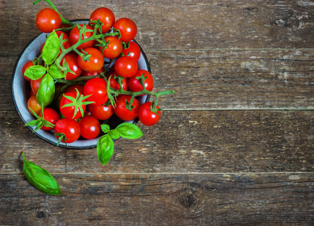 Fresh cherry tomatoes in a metal bowl on a dark wooden background basilの写真素材