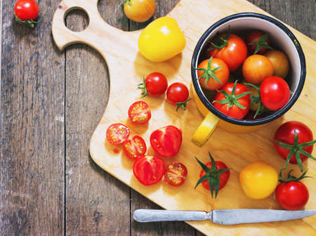 colorful tomatoes in a metal mug on an old wooden tableの写真素材