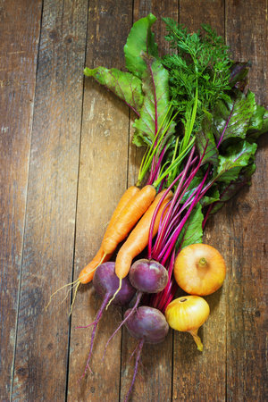Different  fresh young vegetables  beets  carrots, onions  lie on a wooden table. rustic style