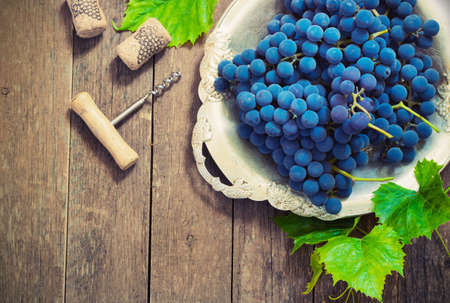 blue grapes in a metal bowl on a wooden backgroundの写真素材
