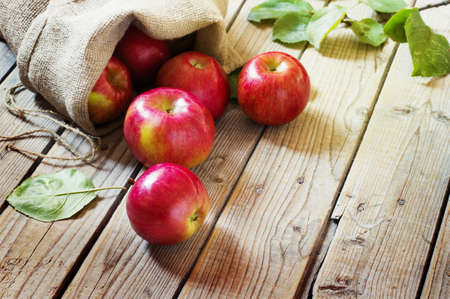 Ripe red apples in a bag on old wooden backgroundの写真素材