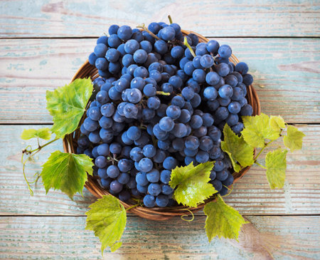 blue grapes in a basket on a wooden background