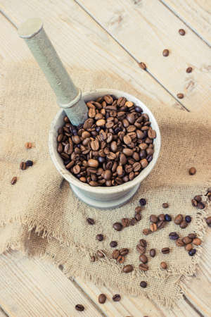coffee beans in a metal mortar on wooden background toningの写真素材