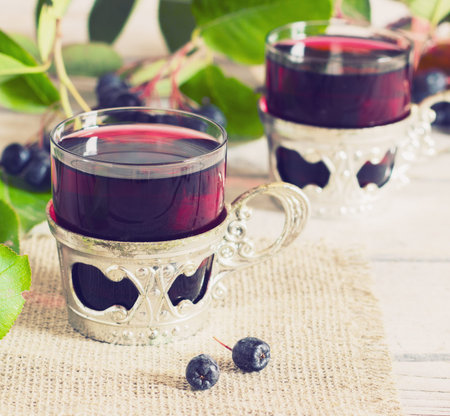 in a glass on a wooden background with branches chokeberry toningの写真素材