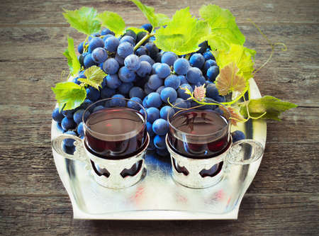 red wine and grapes. Wine and grapes in vintage setting with corks on wooden tableの写真素材