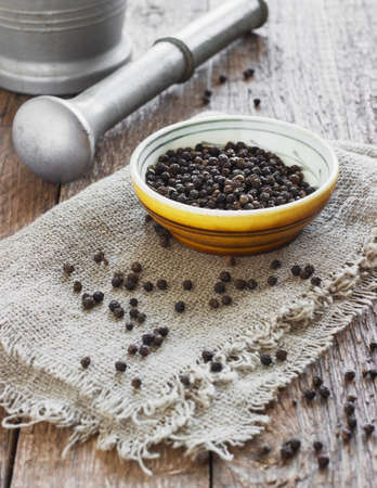 Bowl of black pepper on wooden table metal and mortarの写真素材