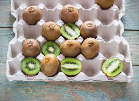 juicy kiwi in a tray on a wooden blue background view from aboveの写真素材