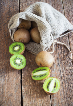 Fresh Juicy Kiwi fruit in bag on brown wooden backgroundの写真素材
