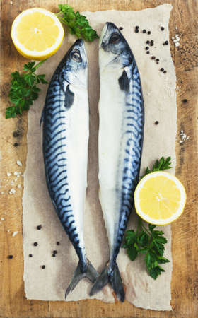 Mackarel at cutting old wooden  table with lemon and parsley toningの写真素材