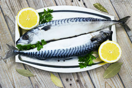 Mackerels fresh served on silver plate with lemon on a wooden backgroundの写真素材