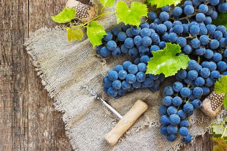 Wine and grapes in vintage setting with corks on wooden tableの写真素材