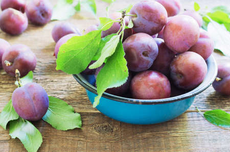 plums on a wooden rustic table in a metal bowl.の写真素材