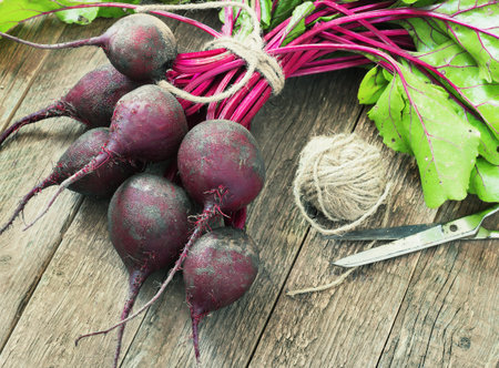Young,fresh beets with tops on old wooden background.Style rustic toning