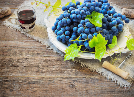red wine and grapes. Wine and grapes in vintage setting with corks on wooden tableの写真素材
