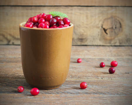 cranberries in a ceramic mug on the old wooden backgroundの写真素材