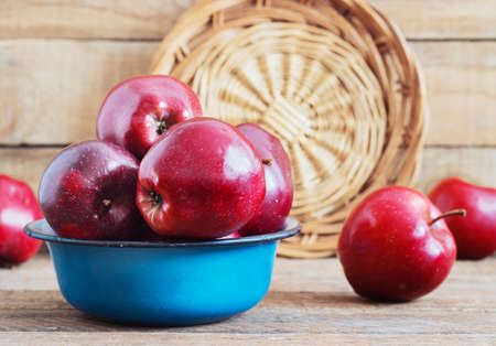 A beautiful red apples in a metal bowl on a wooden backgroundの写真素材