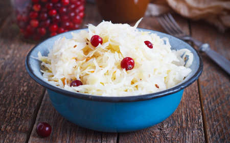 Salad of sauerkraut and carrots, cranberry in rustic style on a wooden background. Selective focus.の写真素材