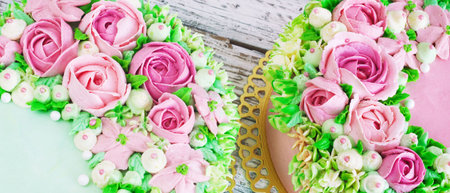 Two celebratory cake with flowers rose on a white wooden background.の写真素材