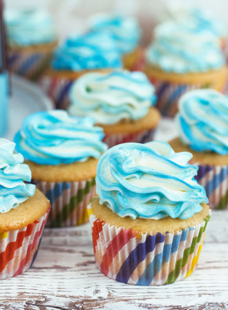 Children's cupcakes with cream cap blue on white wooden backgroundの写真素材
