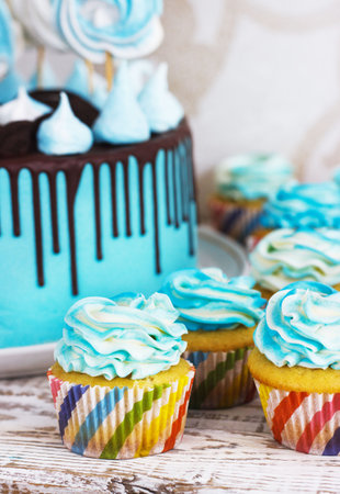 Festive cupcakes and cake with cream in blue on a white wooden background.の写真素材