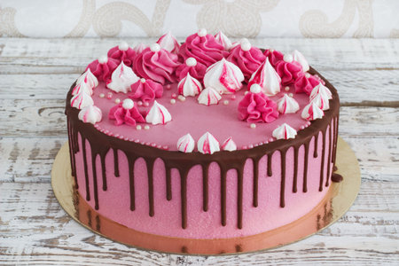 Pink cream cake meringues with smudges of chocolate on a white wooden backgroundの写真素材