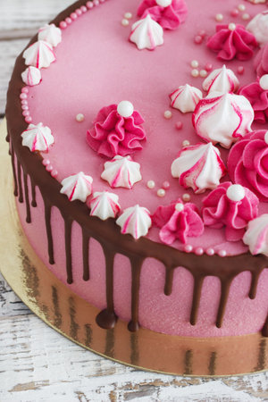 Pink cream cake meringues with smudges of chocolate on a white wooden backgroundの写真素材