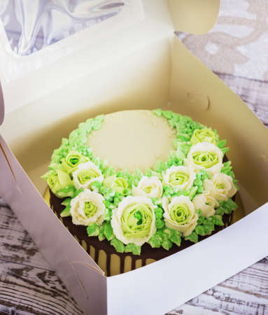 Celebratory cake with roses in the box made of cream on a white wooden backgroundの写真素材