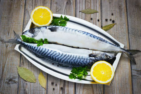 Mackerels fresh served on silver plate with lemon on a wooden backgroundの写真素材