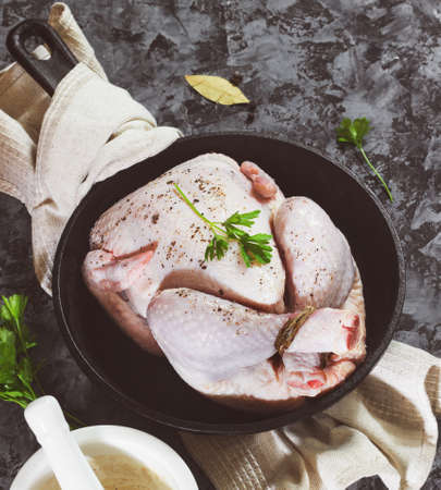 Raw chicken on a cast-iron frying pan on a black concrete backgroundの写真素材