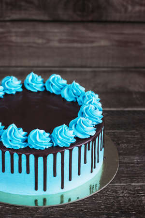 Birthday cake with cream chocolate drips on a dark wooden background.の写真素材