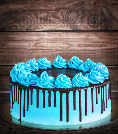 Birthday cake with cream chocolate drips on a dark wooden background.の写真素材
