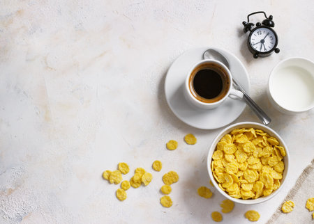 Corn flakes, coffee, alarm clock on a light background, breakfast.